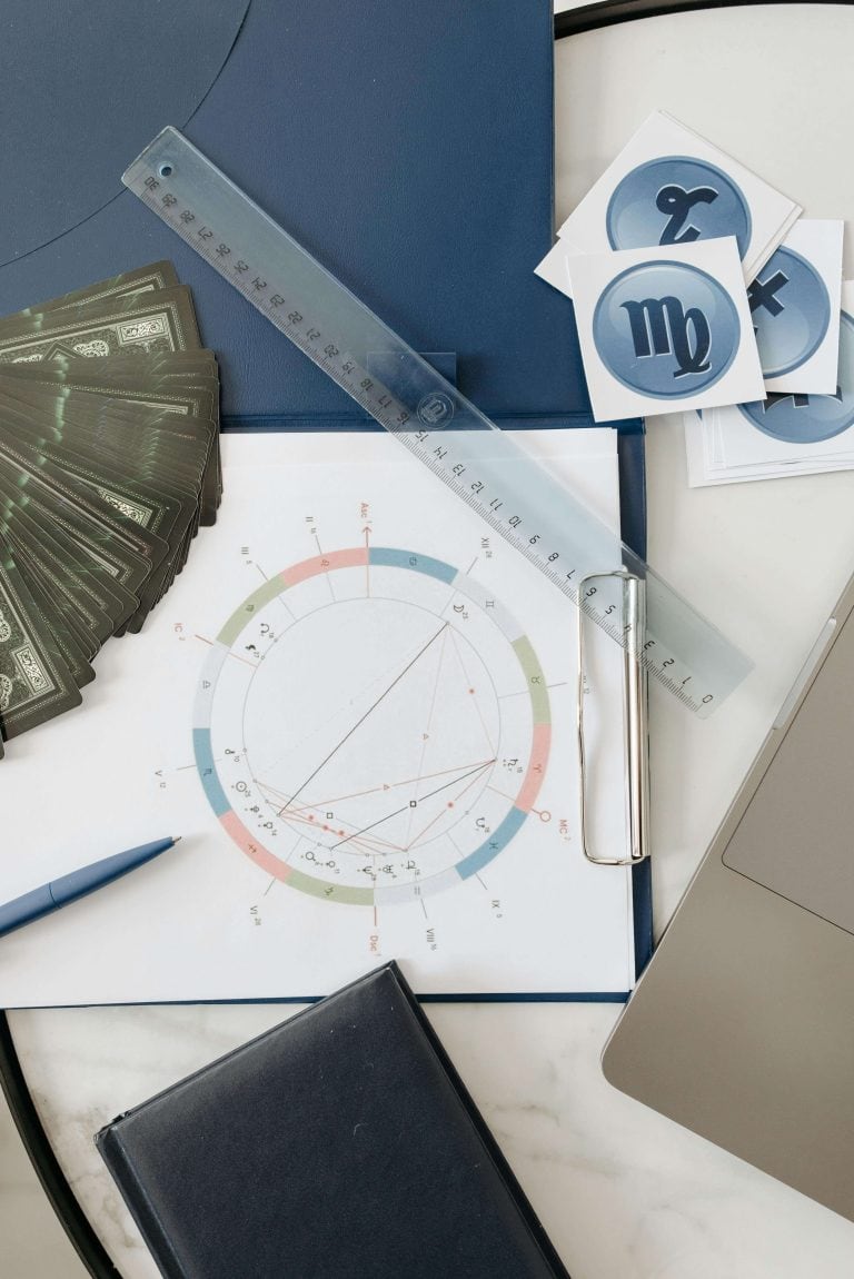 A detailed astrology chart setup with zodiac symbols, tarot cards, and measurement tools for spiritual guidance.