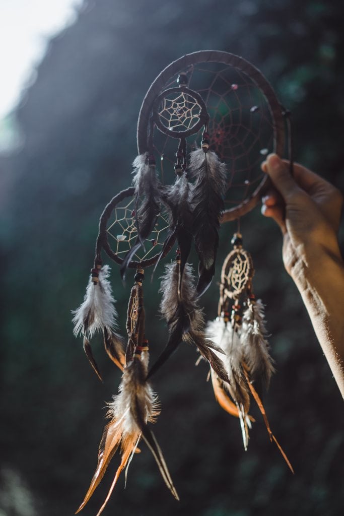 Dreamcatcher with feathers, symbolizing spiritual protection and ancient wisdom in a natural environ.